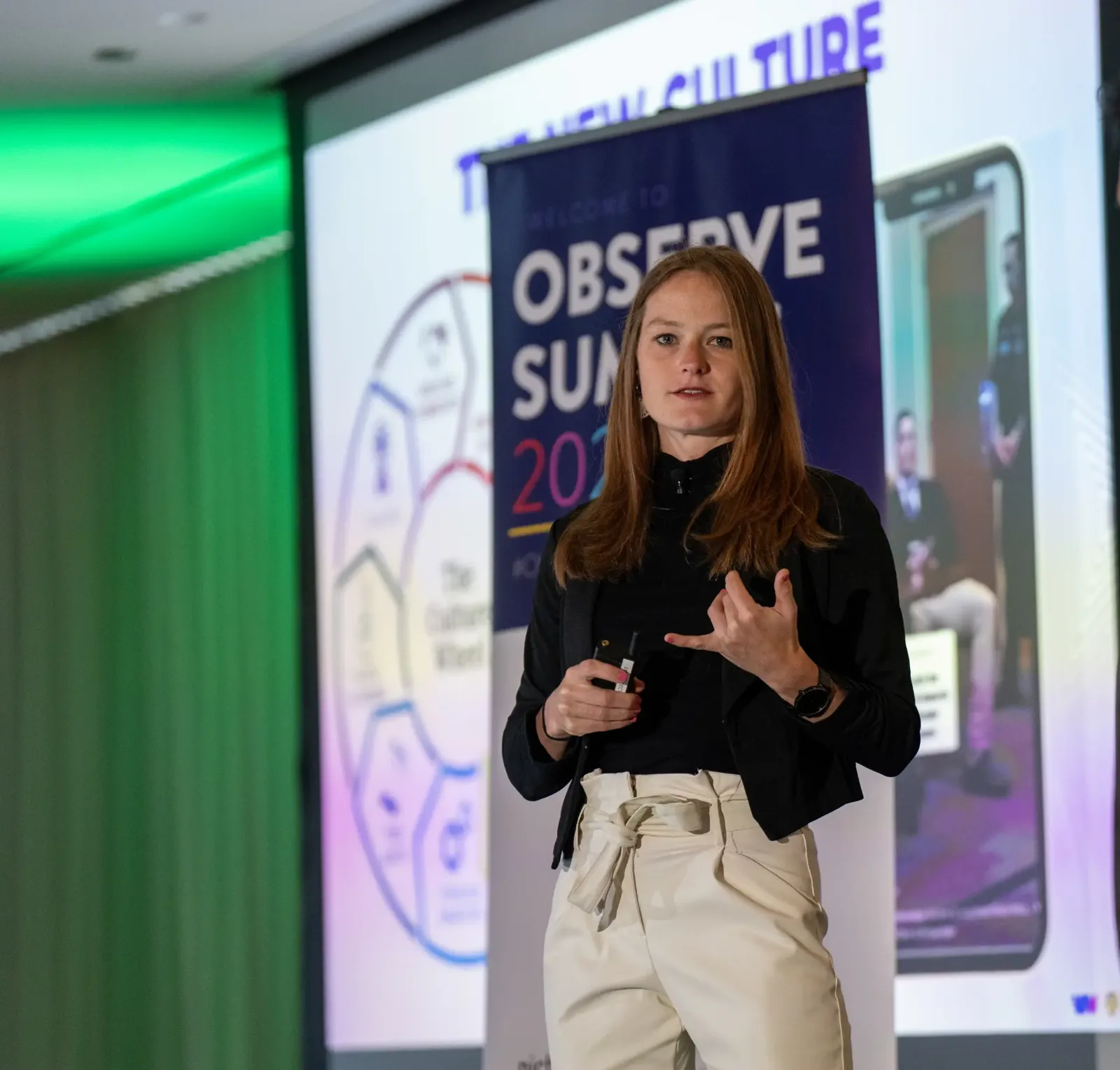 Elizabeth Arnold presenting on stage holding a presentation remote