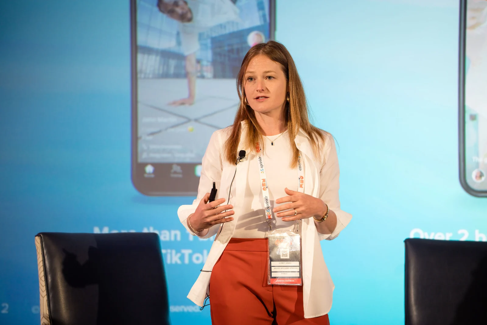 Elizabeth Arnold speaking and gesturing in front of a blue presentation screen